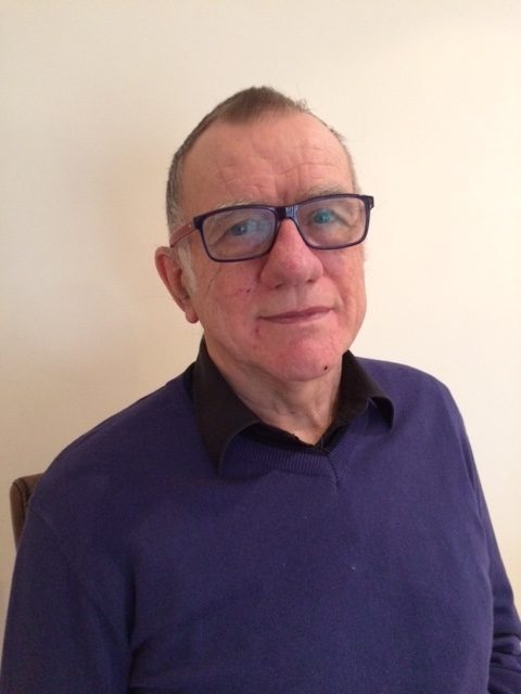 higher education lecturer wearing glasses standing and loking at a camera
